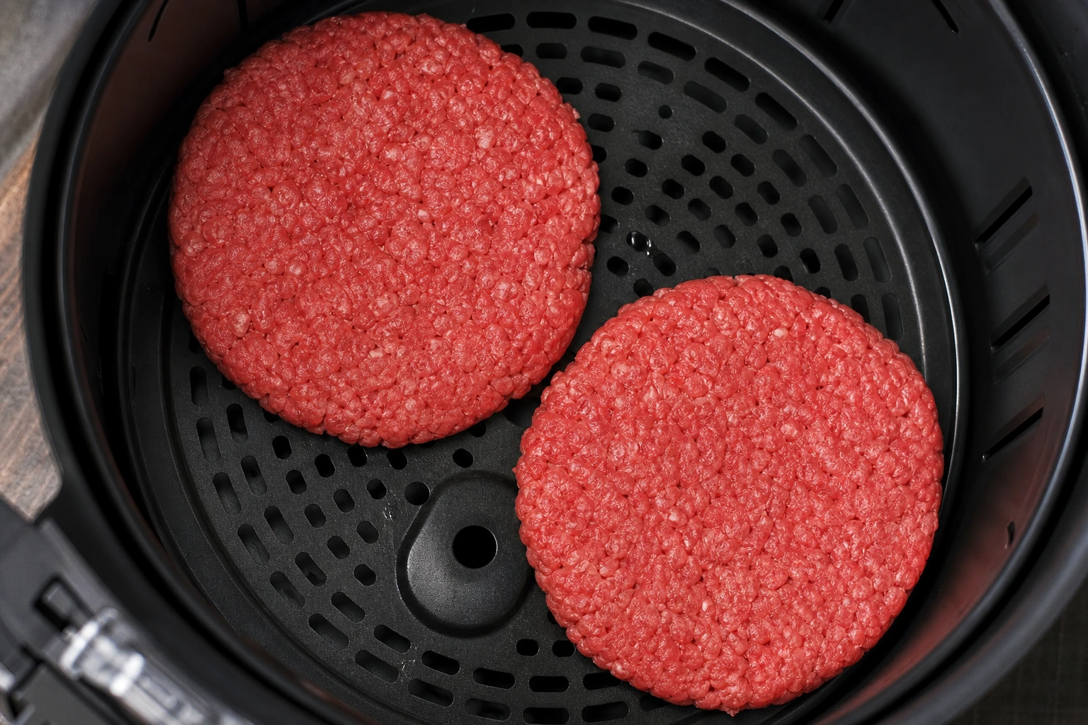 Steaks hachés de bœuf placés dans le panier de l'Air Fryer